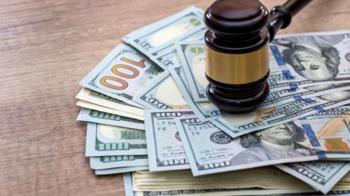 A gavel on top of a stack of hundred dollar bills